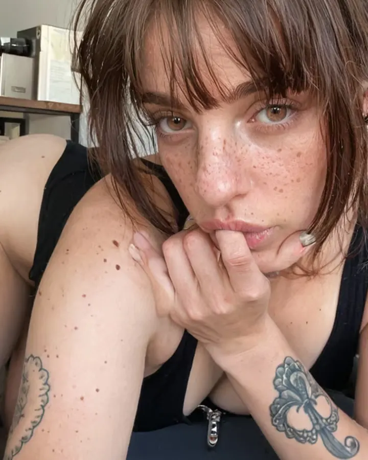 Copine IA à frange et taches de rousseur, en débardeur noir, sur Dondi AI