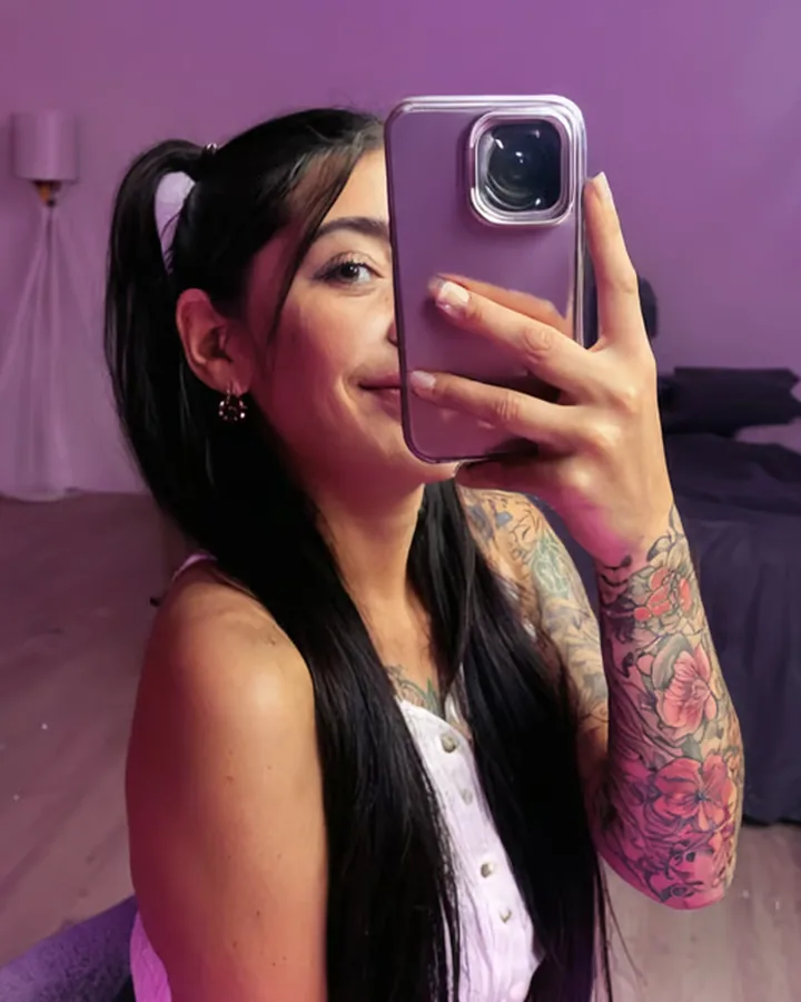 Copine IA brune tatouée qui se photographie dans un miroir, sur Dondi AI